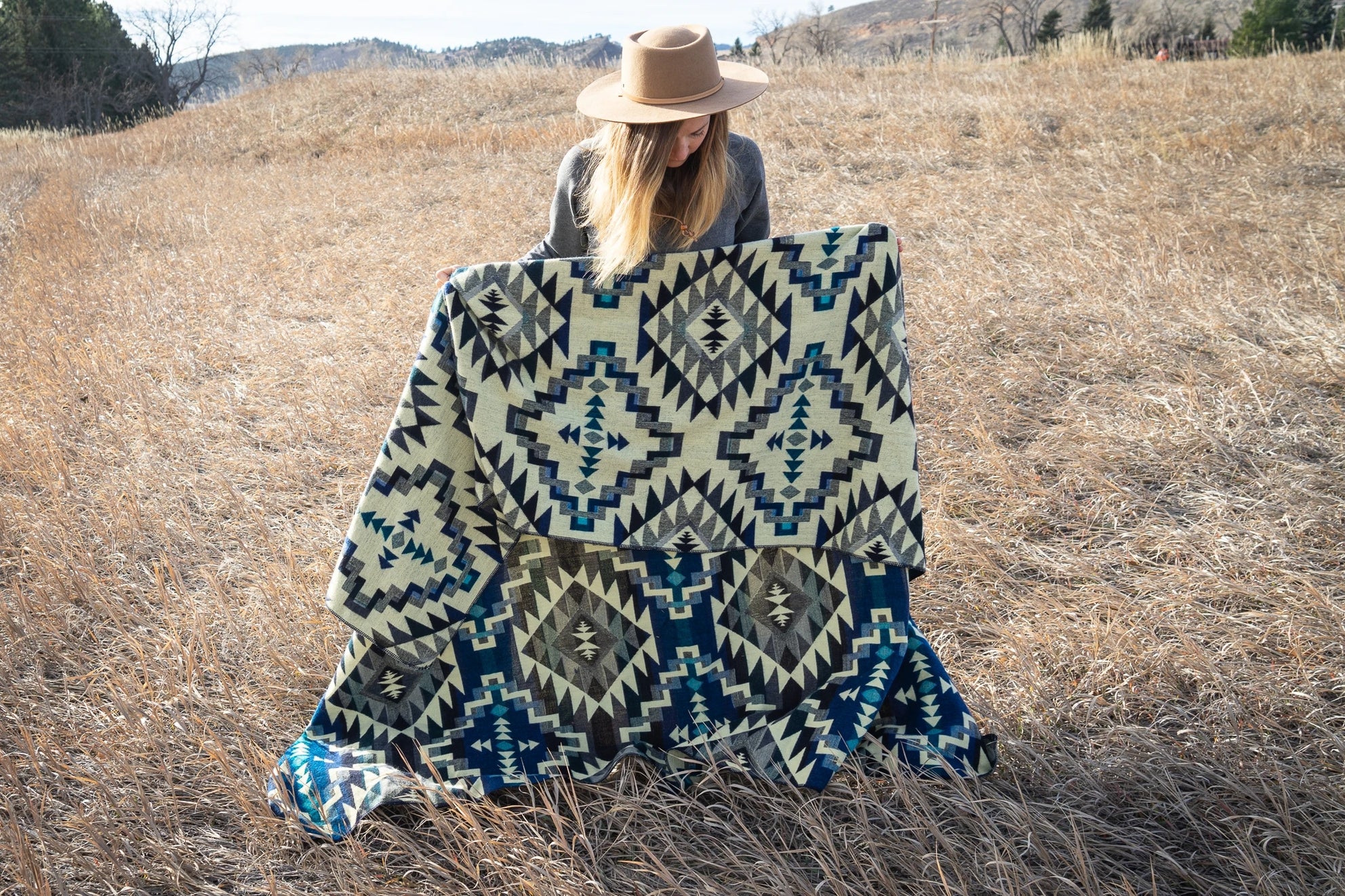 Person holding a patterned blanket in a field