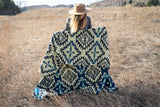 Person holding a patterned blanket in a field
