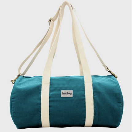 Teal duffel bag with white straps on a light gray background